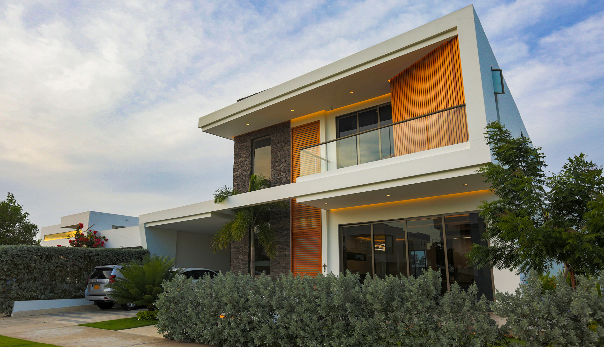 Fachada frontal Casa Sarria 31 03 — volúmenes blancos, listones de madera y revestimiento en piedra. Diseño de Topp Create, arquitectos en Cartagena