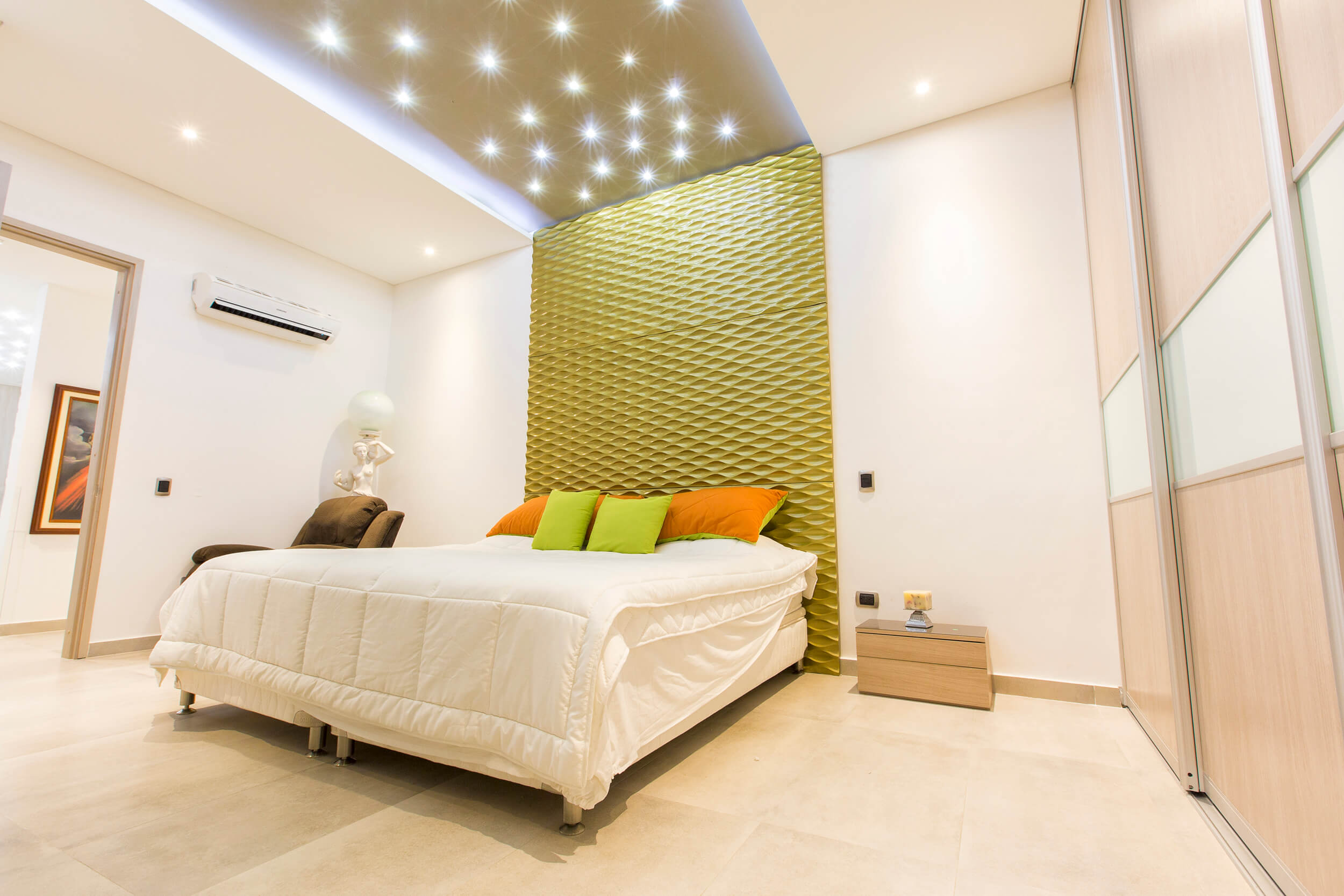 Dormitorio con cabecera texturizada y aire acondicionado — diseño para clima cálido Cartagena