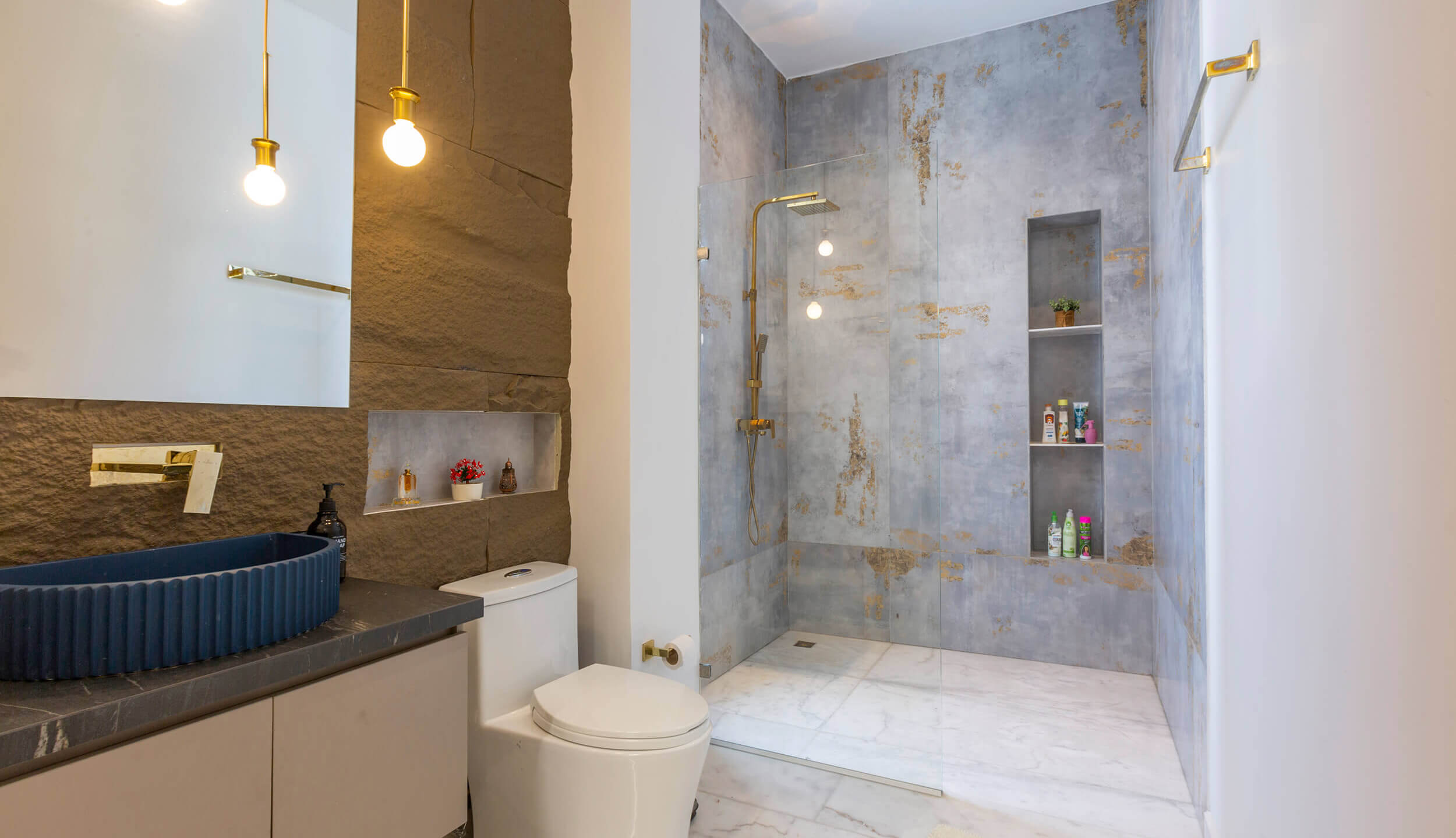 Baño contemporáneo de lujo con acabados en piedra natural, iluminación cálida y ducha moderna diseñado por Topp Create
