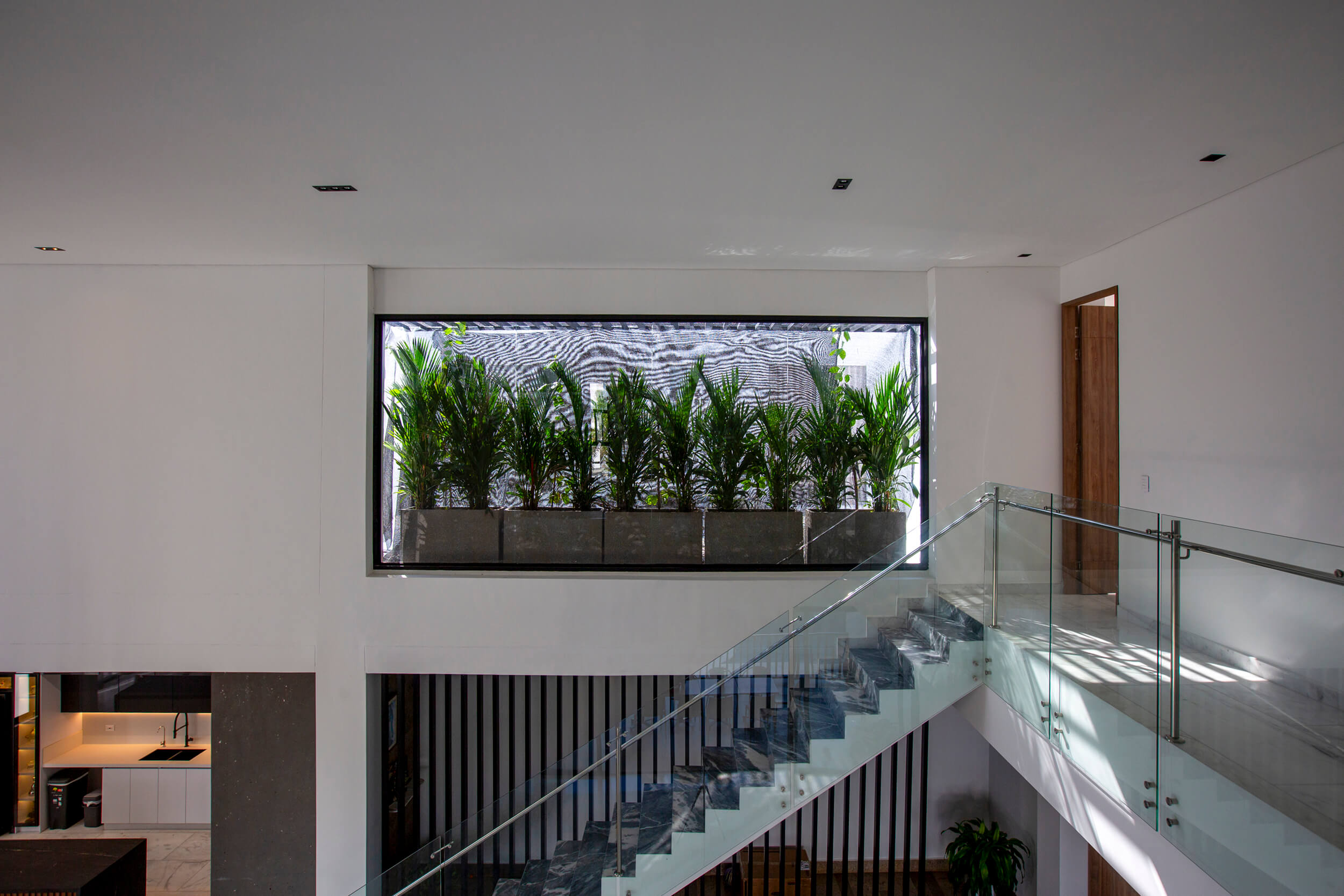 Diseño de interiores. Escalera con vidrio templado y jardín interior en Casa M Barcelona Cartagena