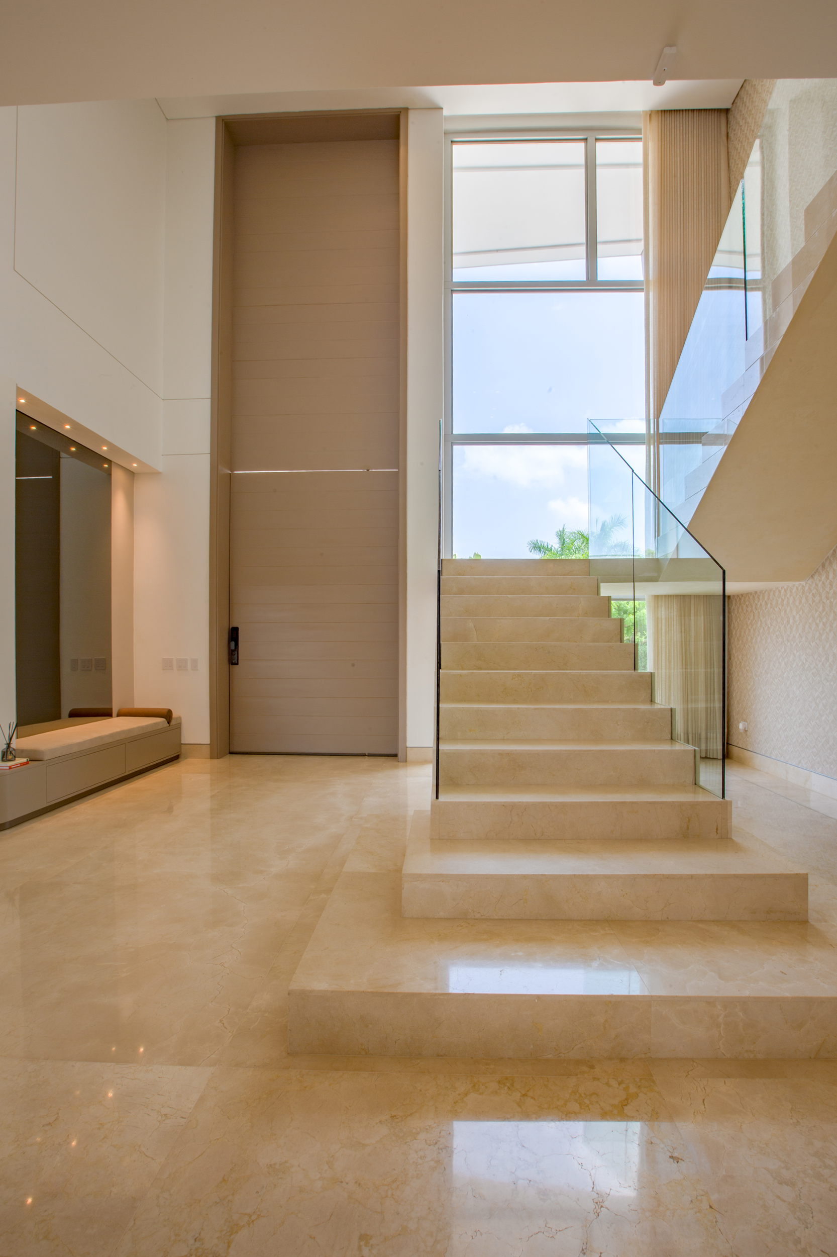 Diseño residencial contemporáneo con escalera flotante y entrada de doble altura