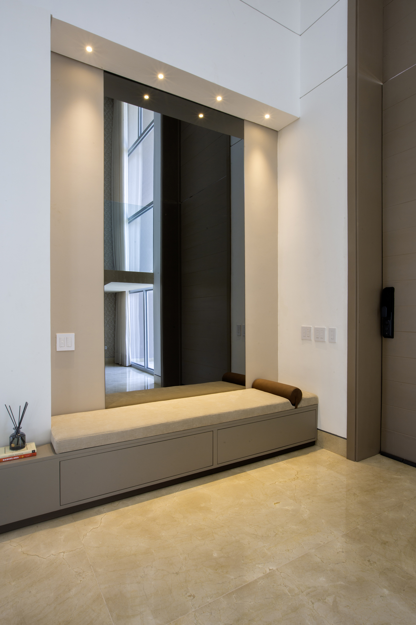 Diseño residencial moderno en recibidor con banco minimalista y espejo vertical